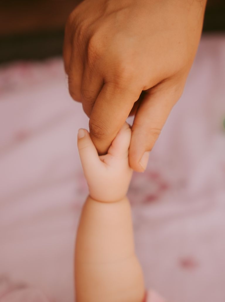 A touching moment featuring a baby's hand grasping an adult's finger, symbolizing connection.